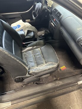 Der Fahrersitz ist aus schwarzem Leder und zeigt deutliche Abnutzungsspuren. Das Leder ist rissig und abgenutzt, was auf ein hohes Alter oder mangelnde Pflege hindeutet