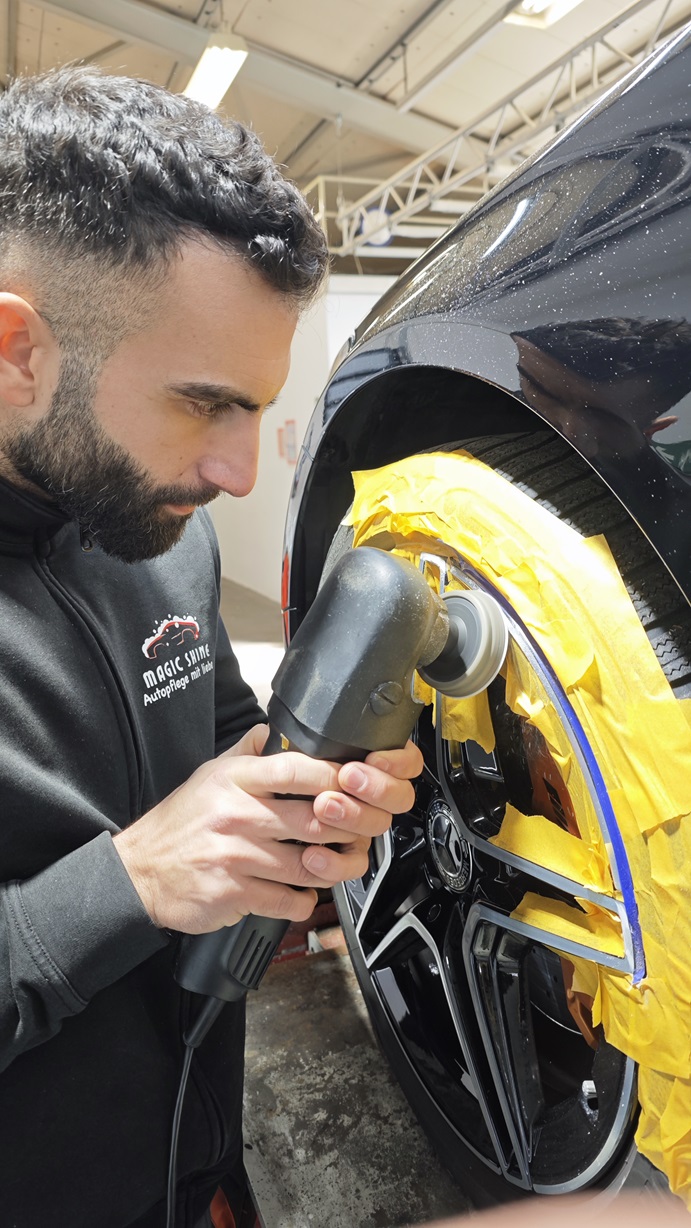 Walid poliert die Felge eines Mercedes Benz mit einer Poliermaschine